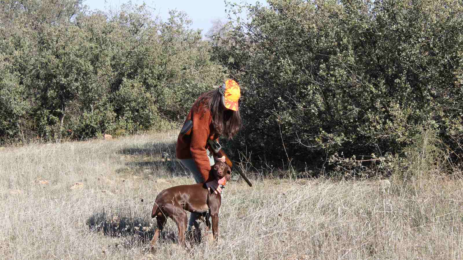 Foto de chica joven cazando con su perro